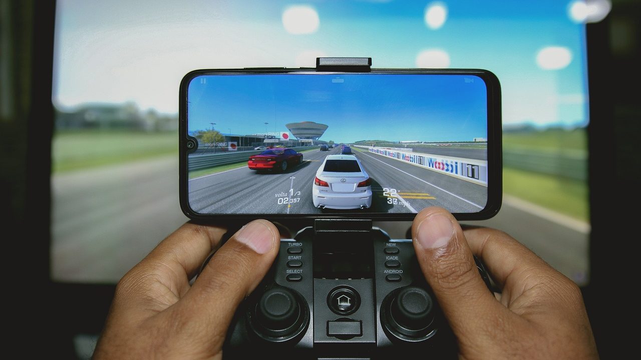 Bilgisayar ekranı yanında akıllı telefonda Android oyunları oynayan kullanıcı